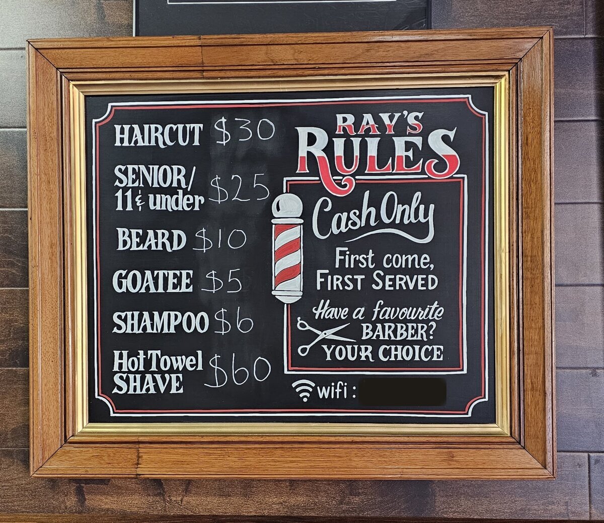 The Ray's Rules chalkboard price list hanging in its wooden frame on the shop wall