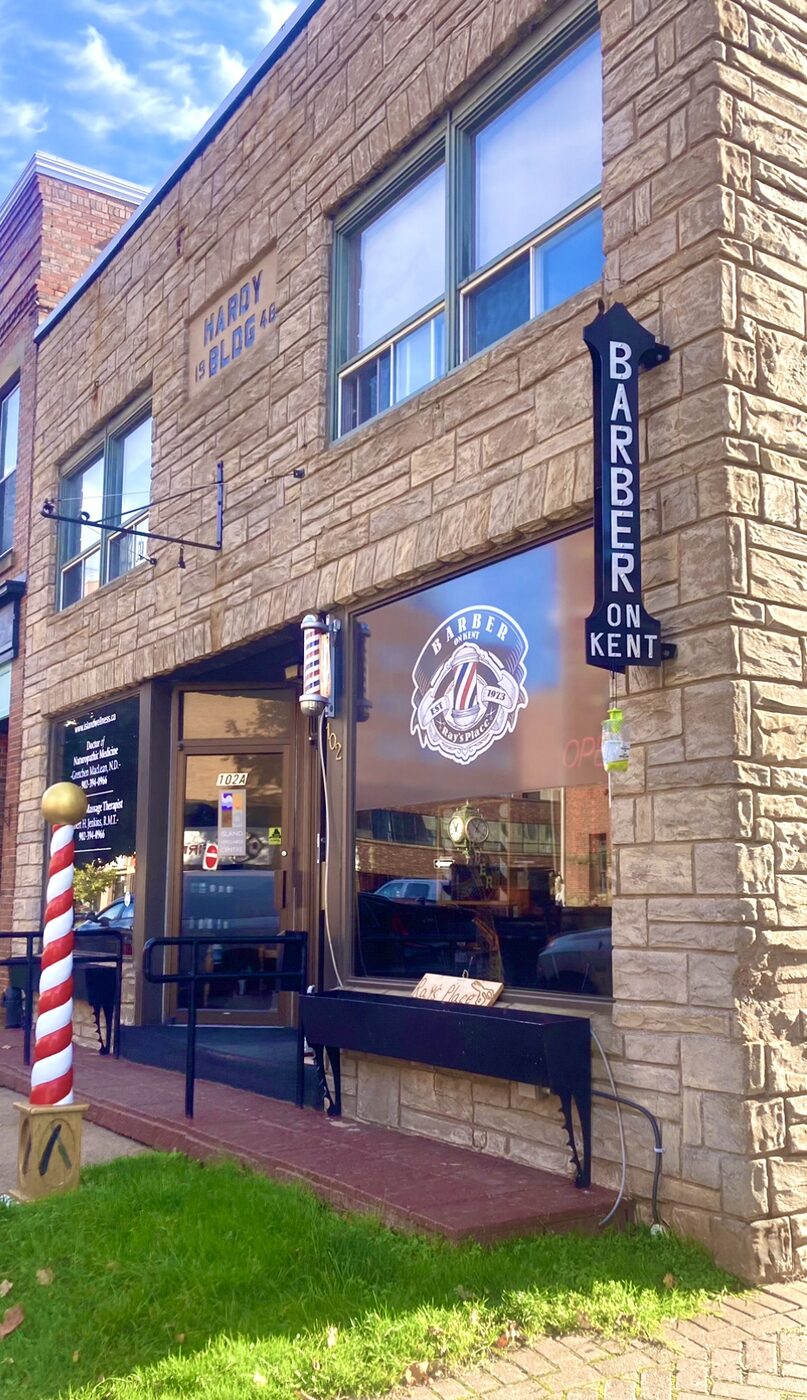 The Barber On Kent blade sign and barber pole on the stone corner of the Hardy Building