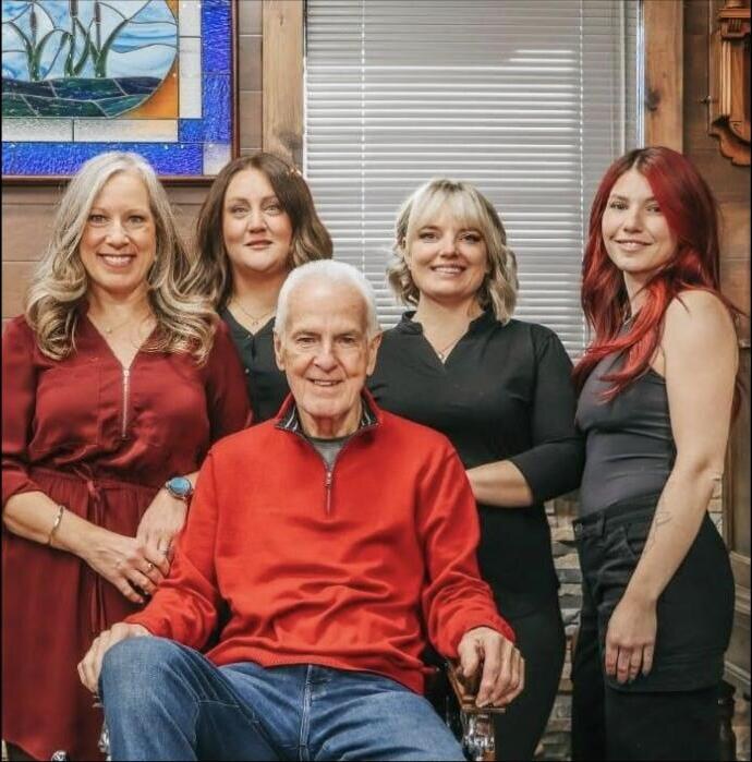 Ray in his red sweater, seated, surrounded by the four barbers who work alongside him